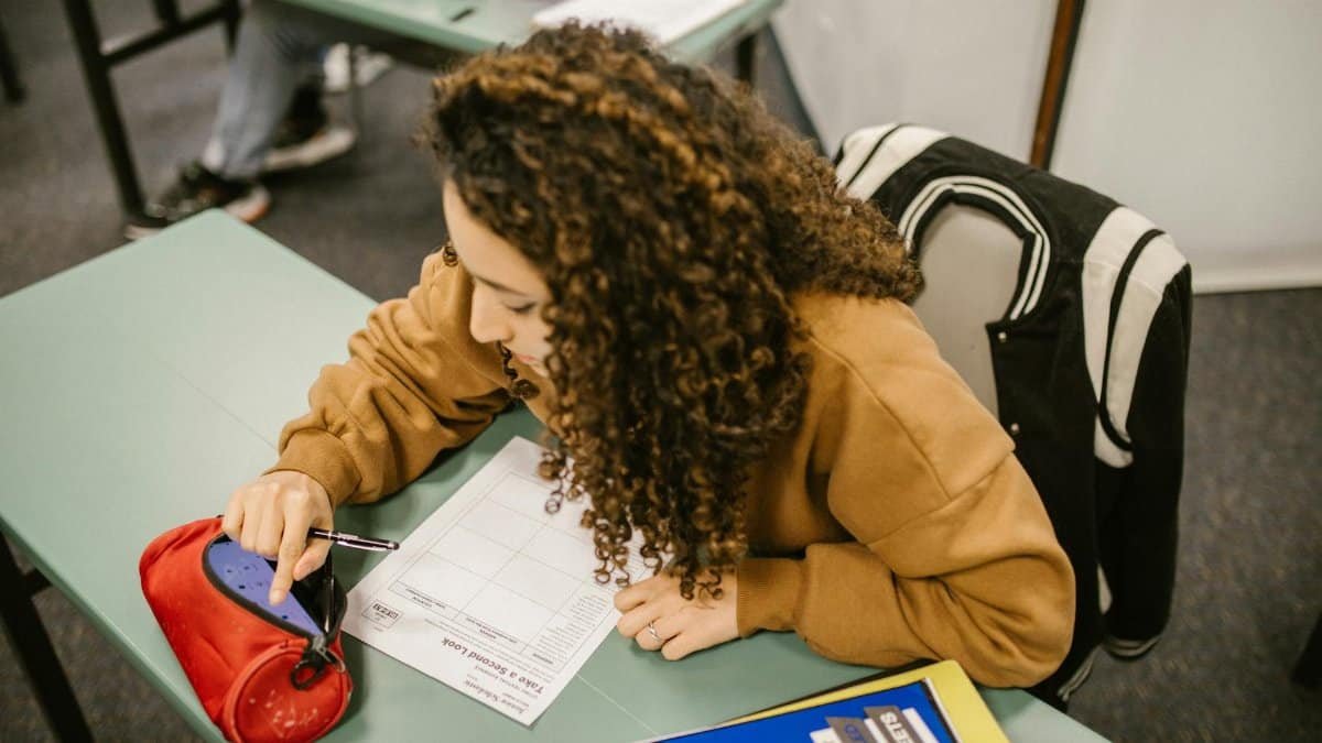 A college student studying for an exam with a smartphone hidden in a pencil case.