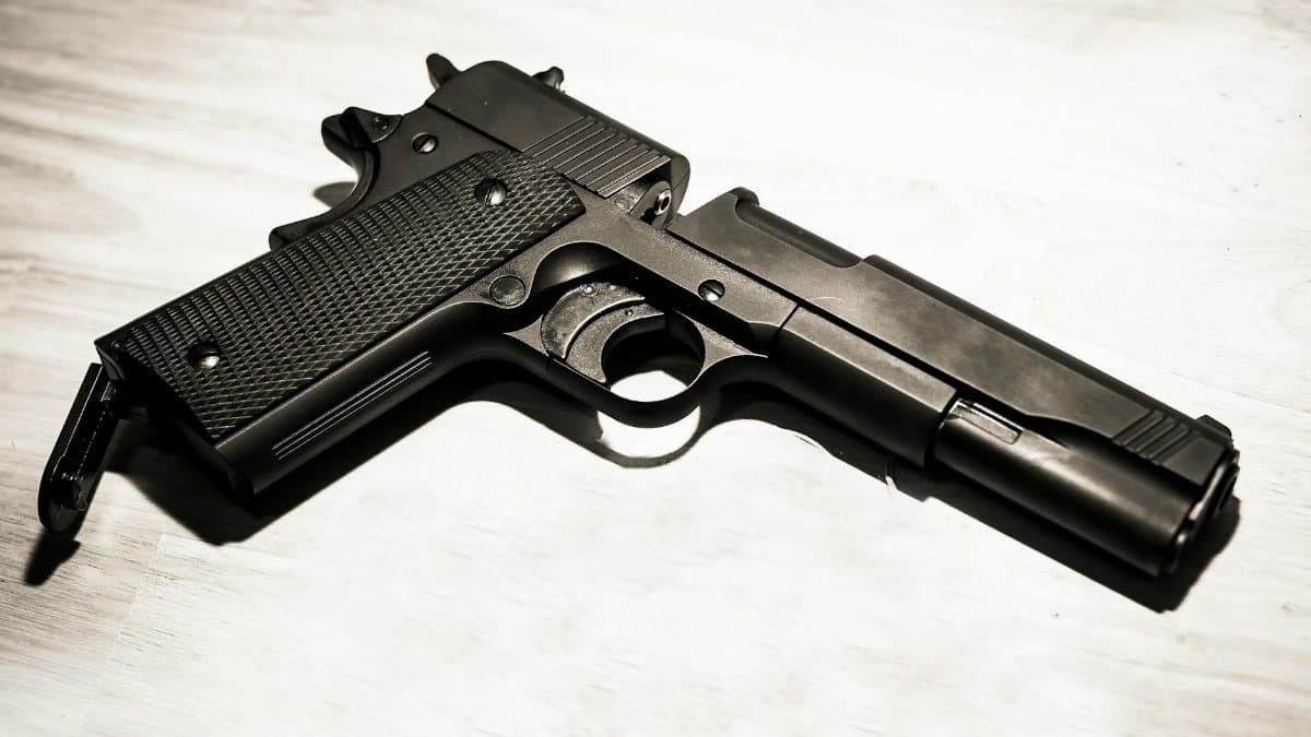 Close-up of a black metal handgun on a light surface, showcasing firearm details.