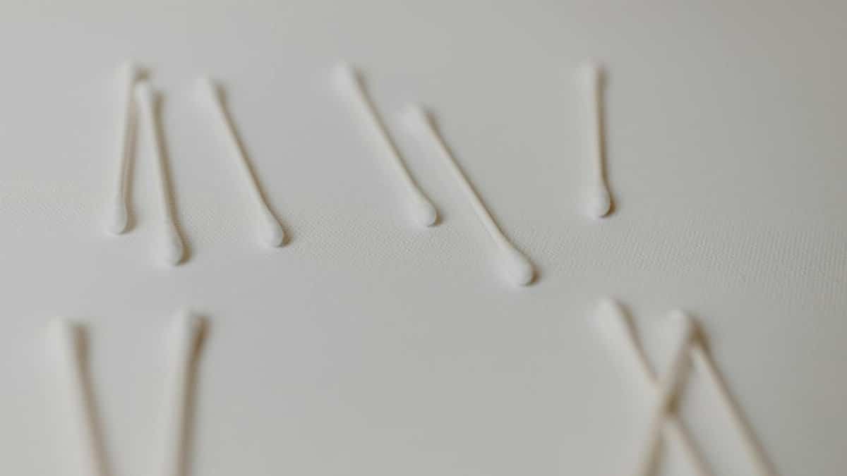 Close-up of cotton swabs arranged on a white surface, emphasizing hygiene and cleanliness.