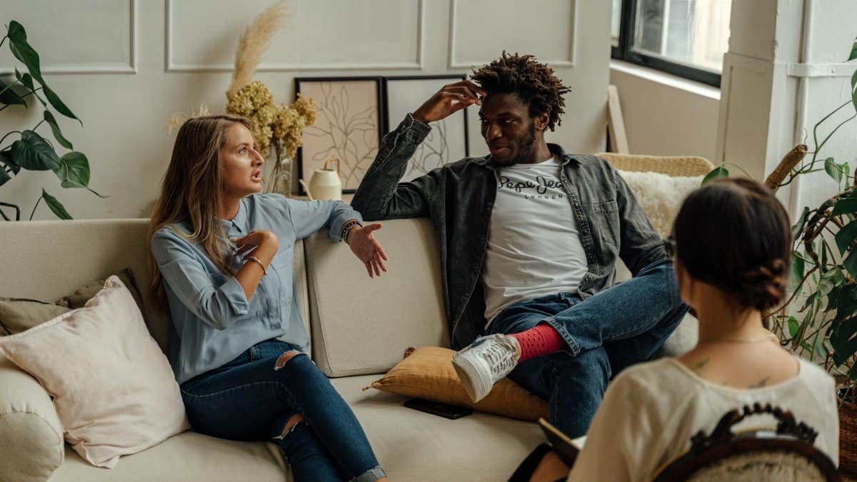 A couple is engaged in a lively conversation during a therapy session with a counselor.