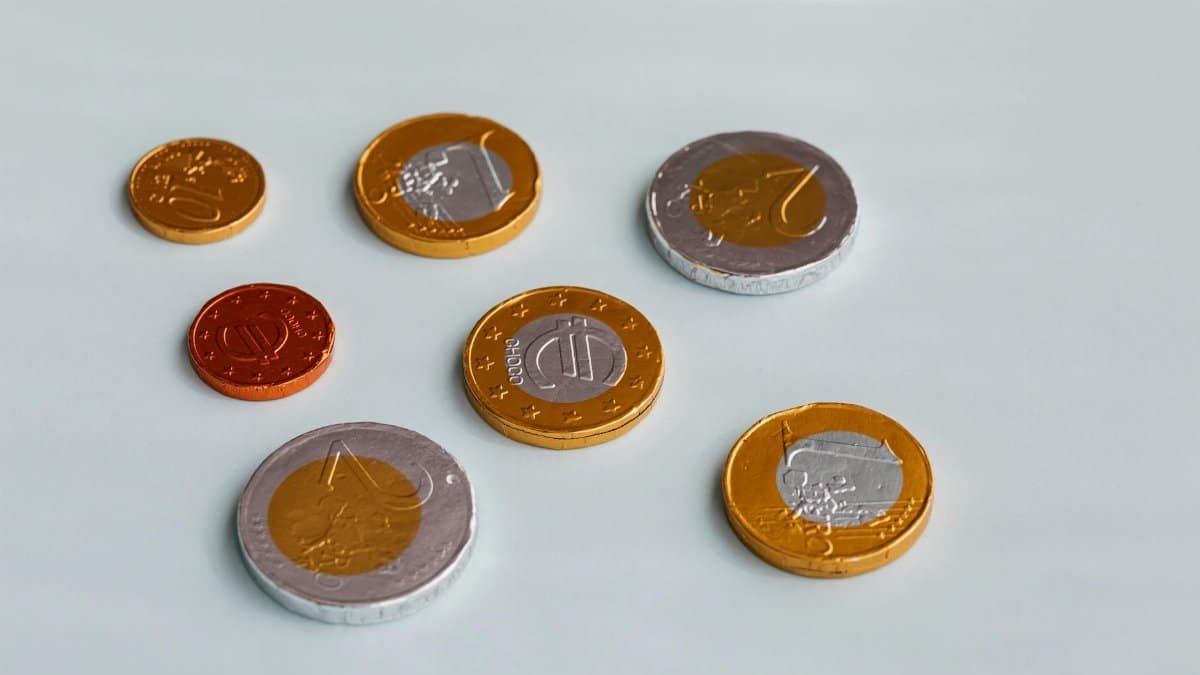 Chocolate coins resembling Euro currency scattered on a white surface, shot from above.