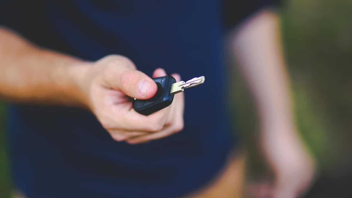 A hand holding a car key outdoors, emphasizing security and control.