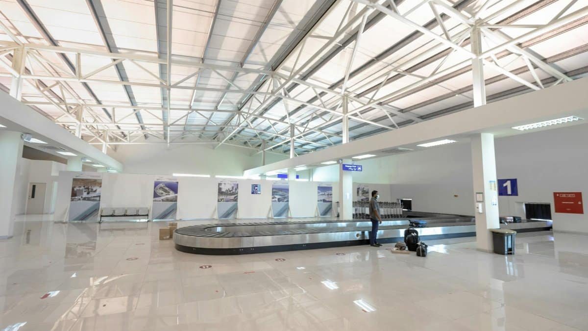 A modern and empty airport baggage claim area with a traveler waiting.