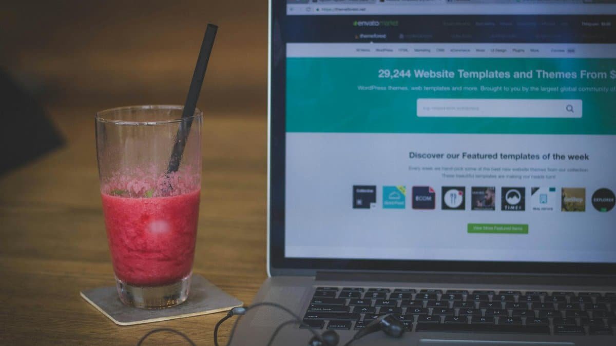 A fruit shake on a desk next to a laptop displaying a website, blending work and refreshment.