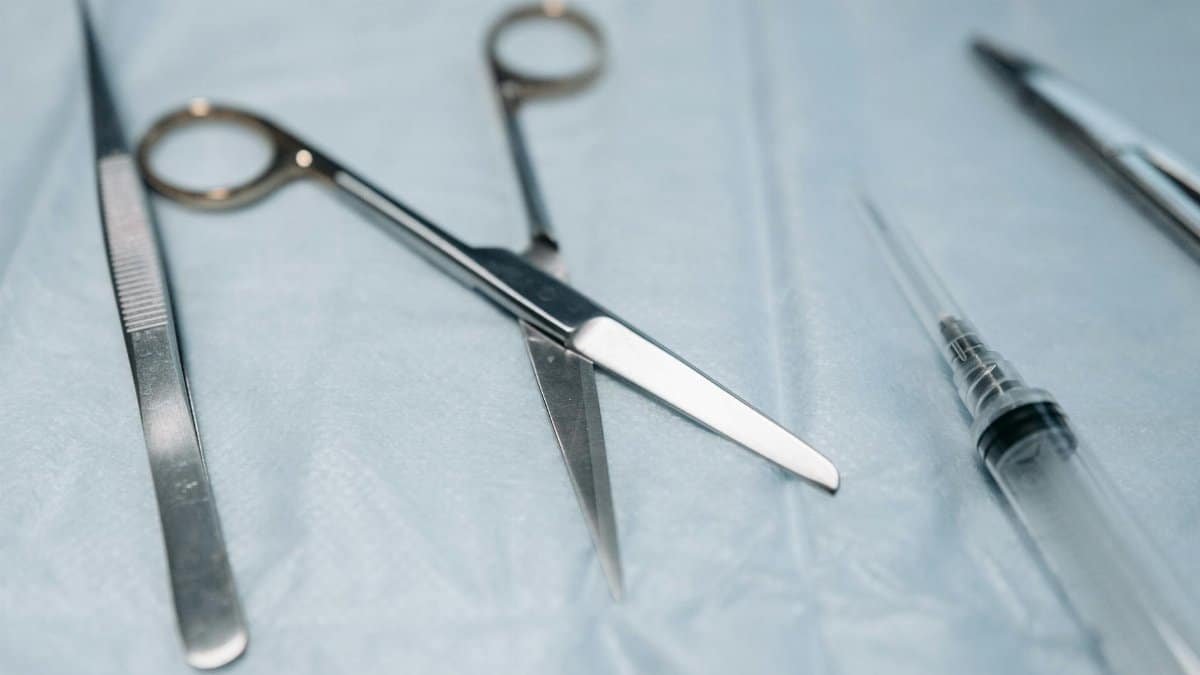Detailed view of surgical tools including scissors on a blue sterile surface.