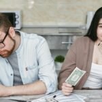A couple managing their finances in a kitchen setting, showcasing money, debt, and budgeting challenges.