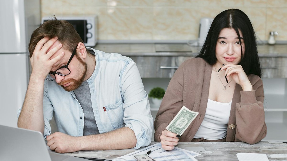A couple managing their finances in a kitchen setting, showcasing money, debt, and budgeting challenges.