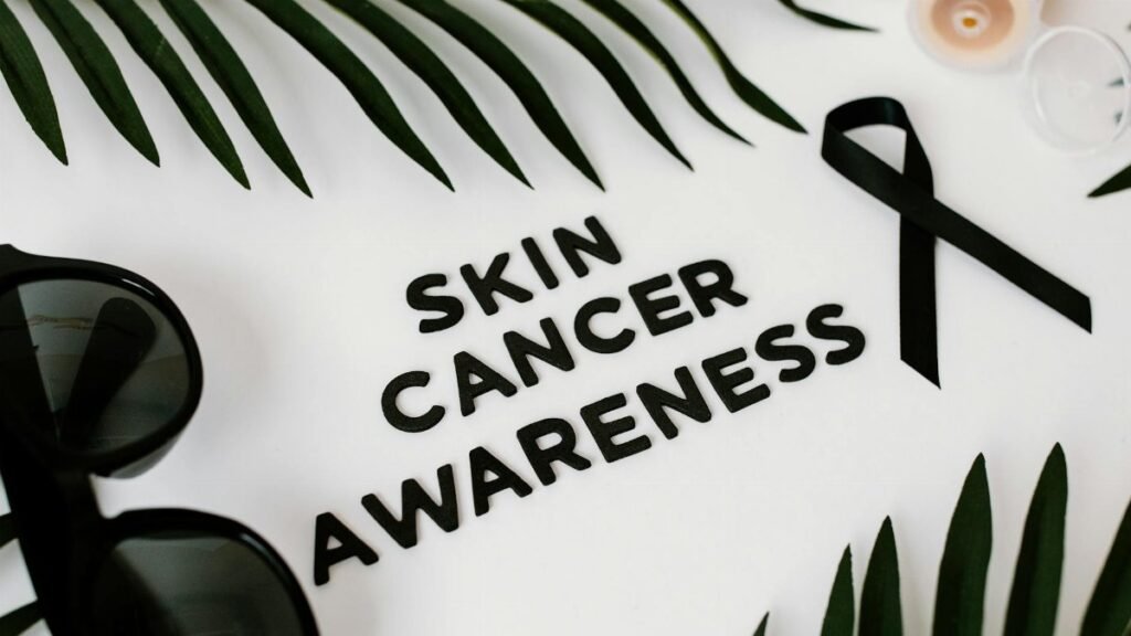 Still life composition promoting skin cancer awareness featuring a black ribbon and sunglasses.