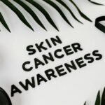 Still life composition promoting skin cancer awareness featuring a black ribbon and sunglasses.