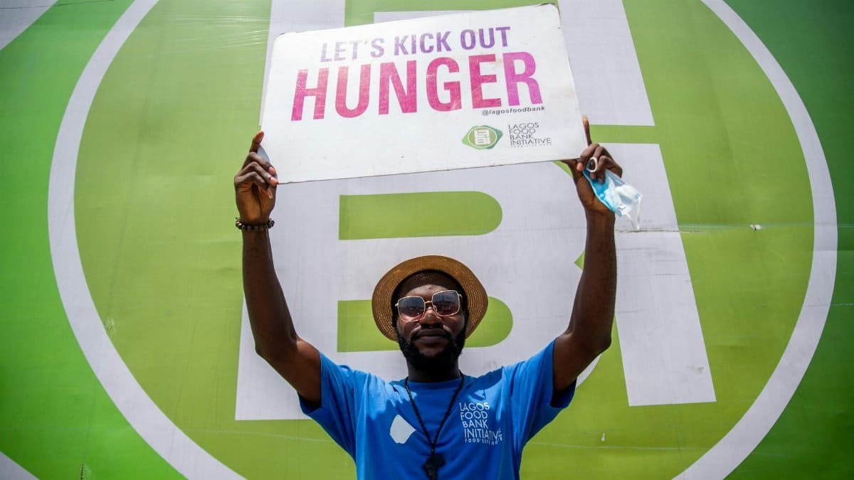 Man holding a sign promoting a hunger awareness campaign at an outdoor event.