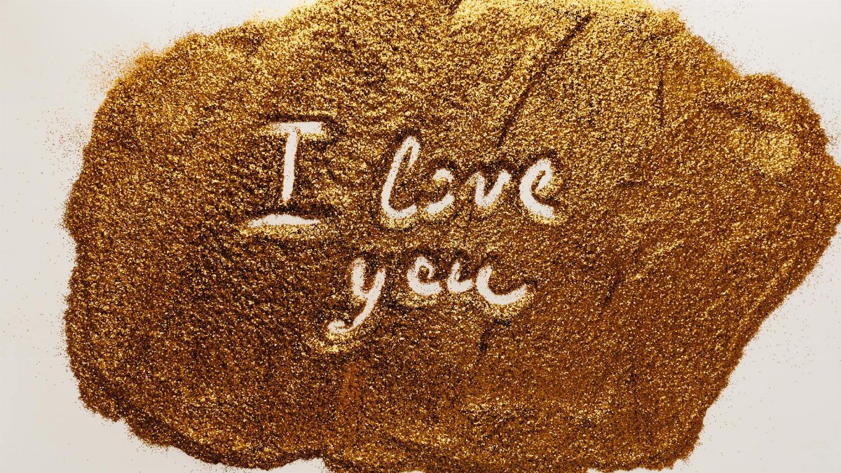 Artistic photo of golden sand with an engraved 'I love you' message.