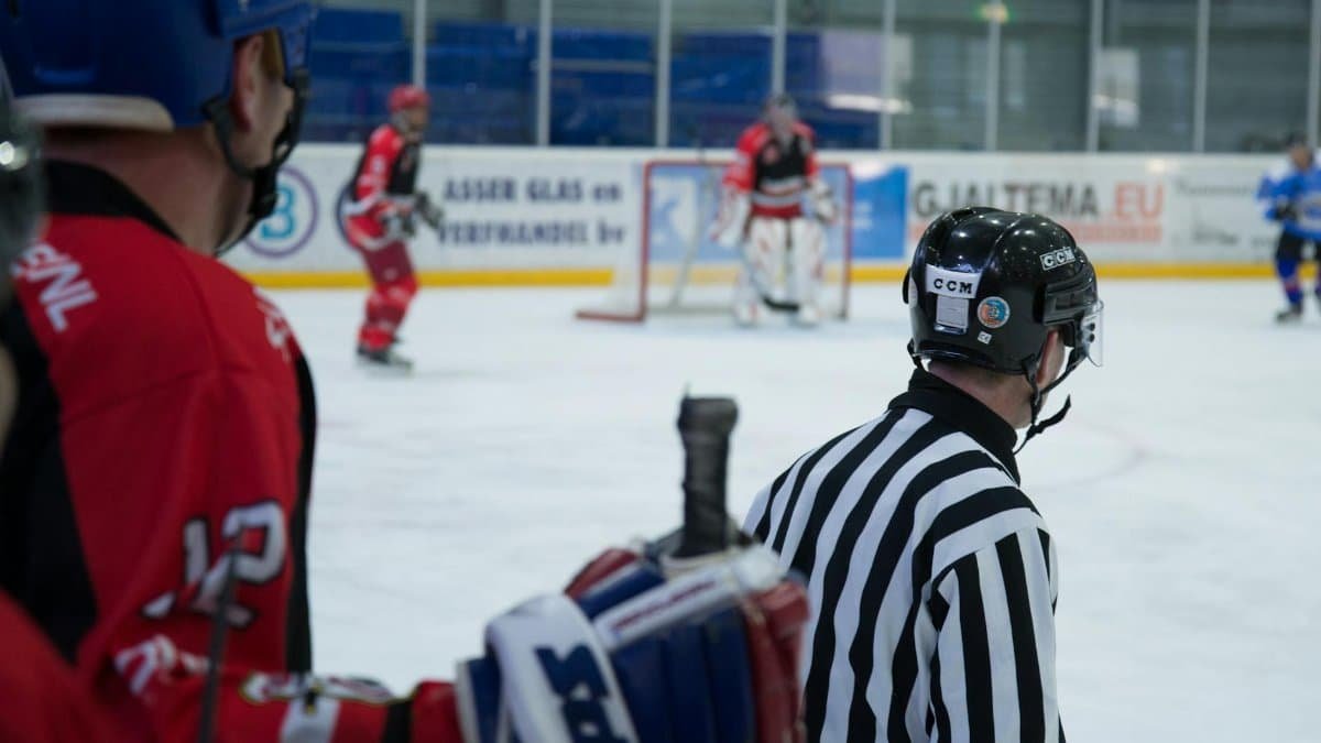 Dynamic shot of an ice hockey game with active players and attentive referee at an indoor rink.