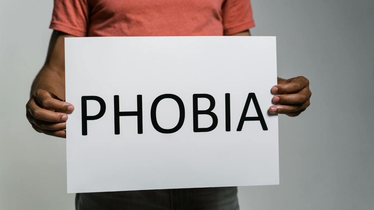Adult holding a sign with 'Phobia' to convey fear and anxiety concepts.