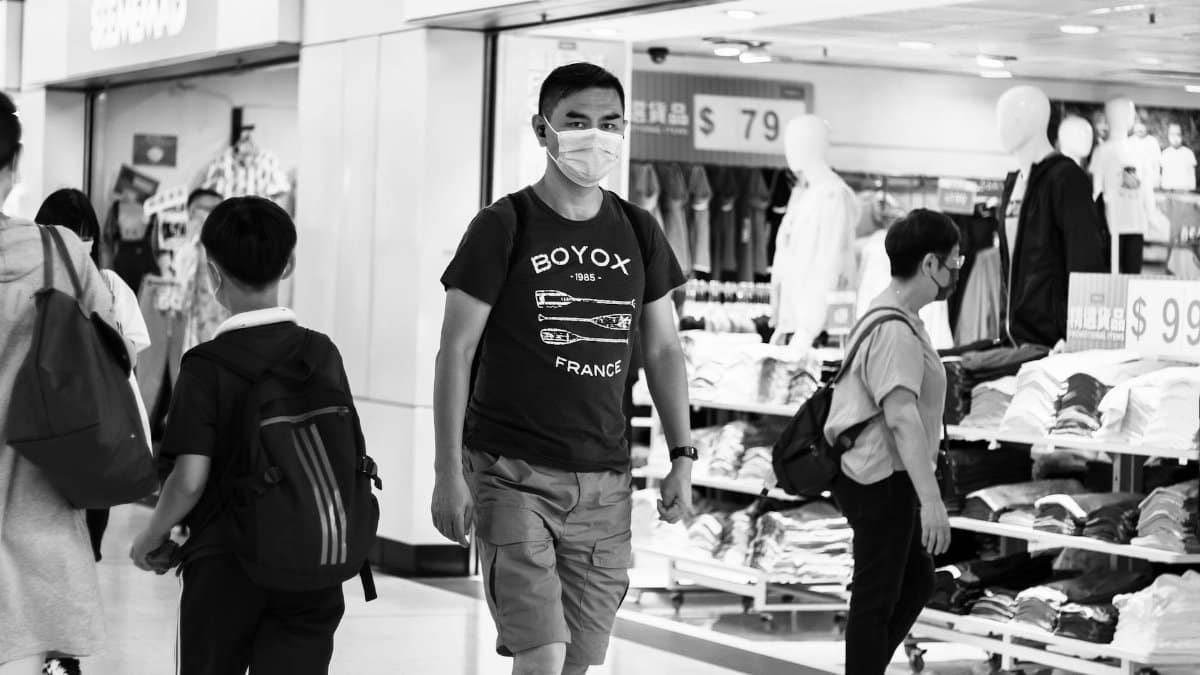 Monochrome image of people wearing face masks shopping indoors during the pandemic.