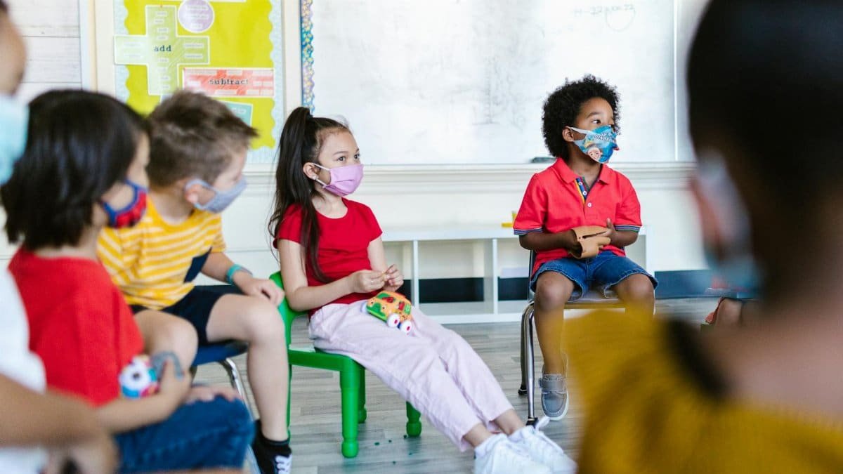 Group of young kids in classroom wearing face masks during a lesson.