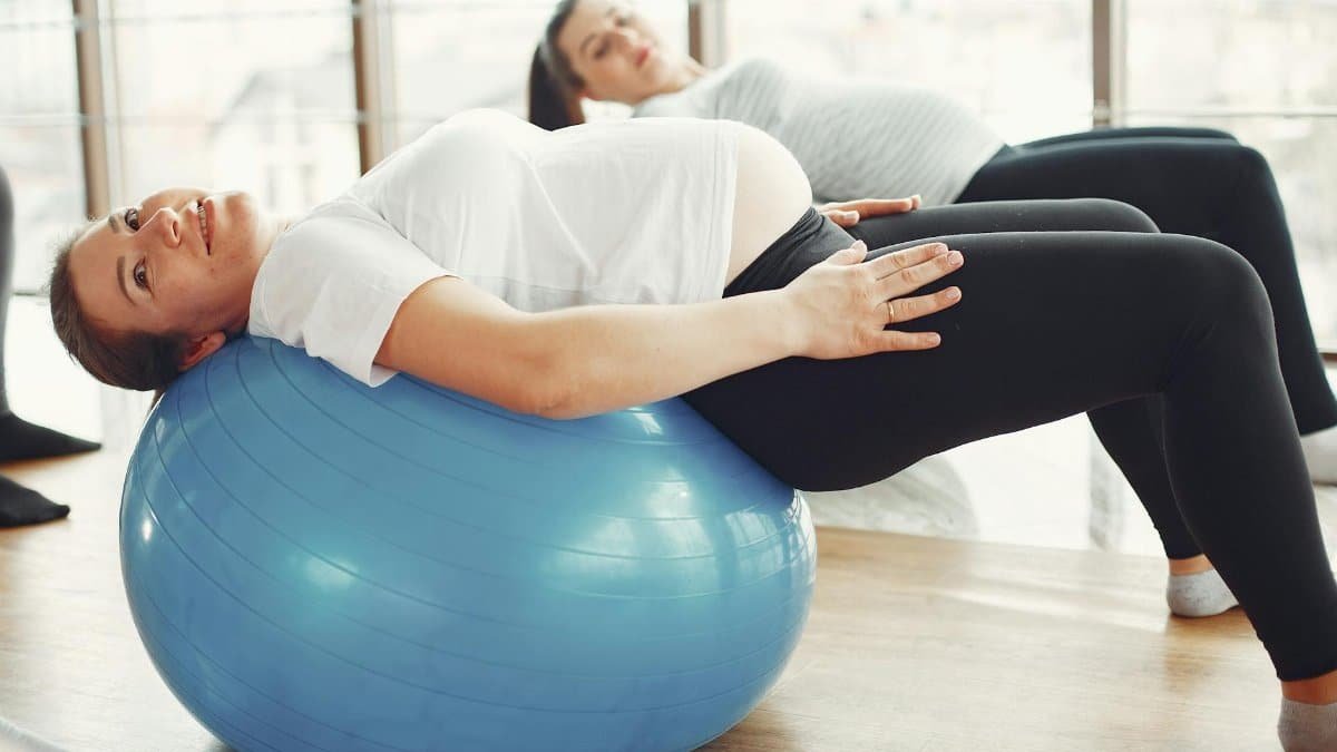 Pregnant women engaging in low-impact exercise with fitness balls indoors.