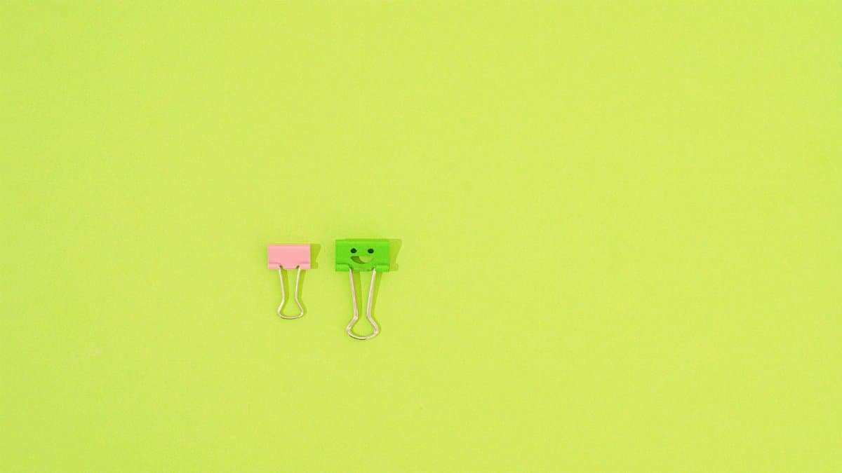 Two binder clips on a bright green background with ample copyspace for text.