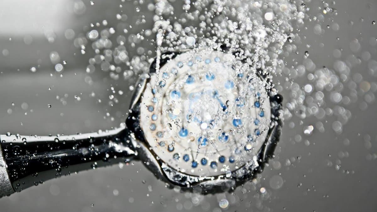Close-up of a shower head releasing water droplets, creating a crisp and refreshing bathroom scene.