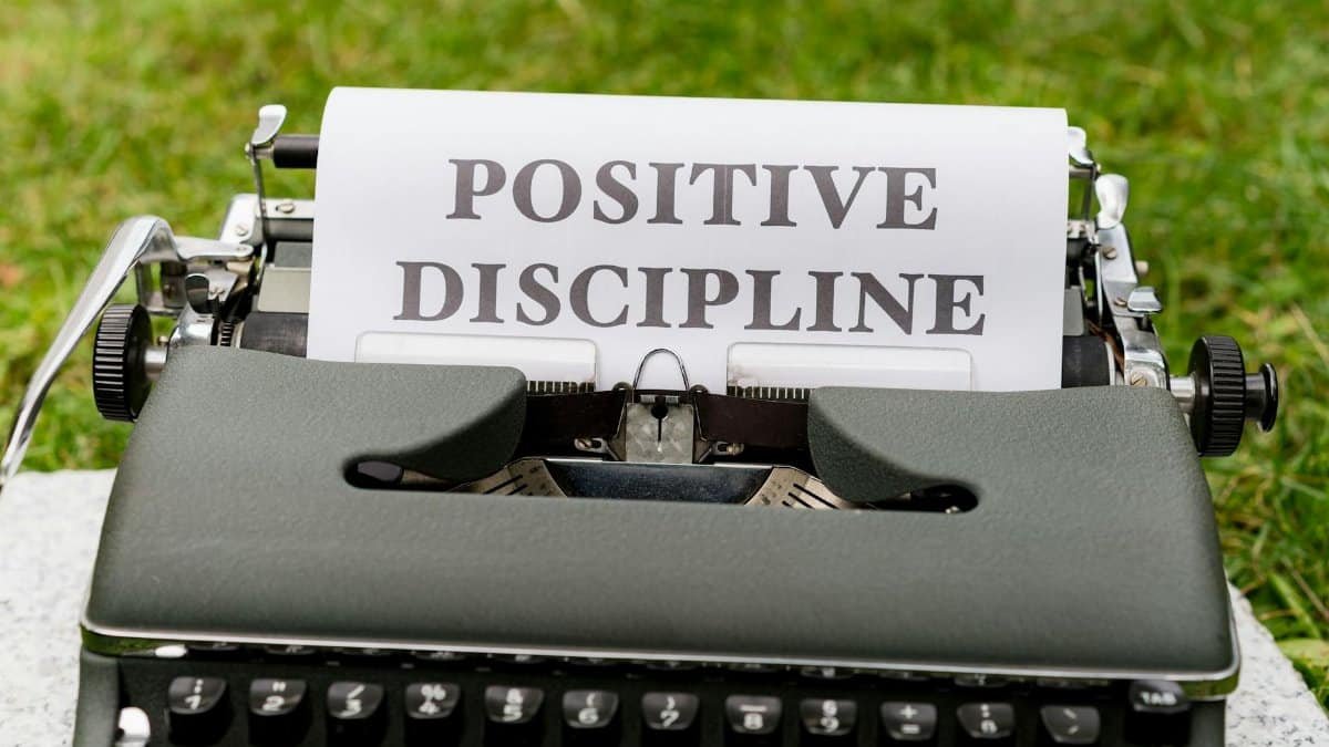 A vintage typewriter outdoors with paper showing 'Positive Discipline'.