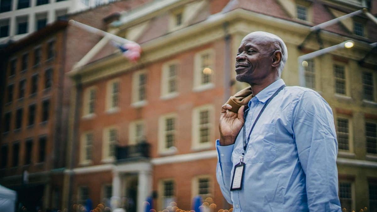 African American man in smart attire standing confidently in a bustling urban environment.