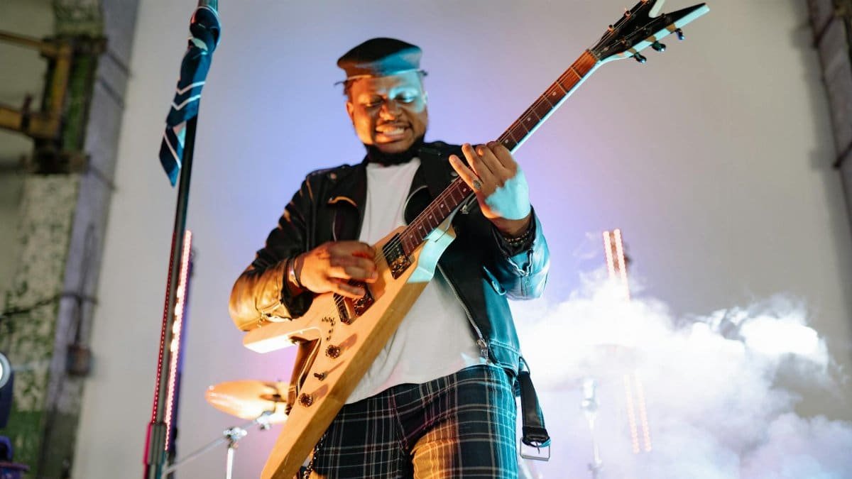 Vibrant live performance of a guitarist in action with smoke effect on stage.