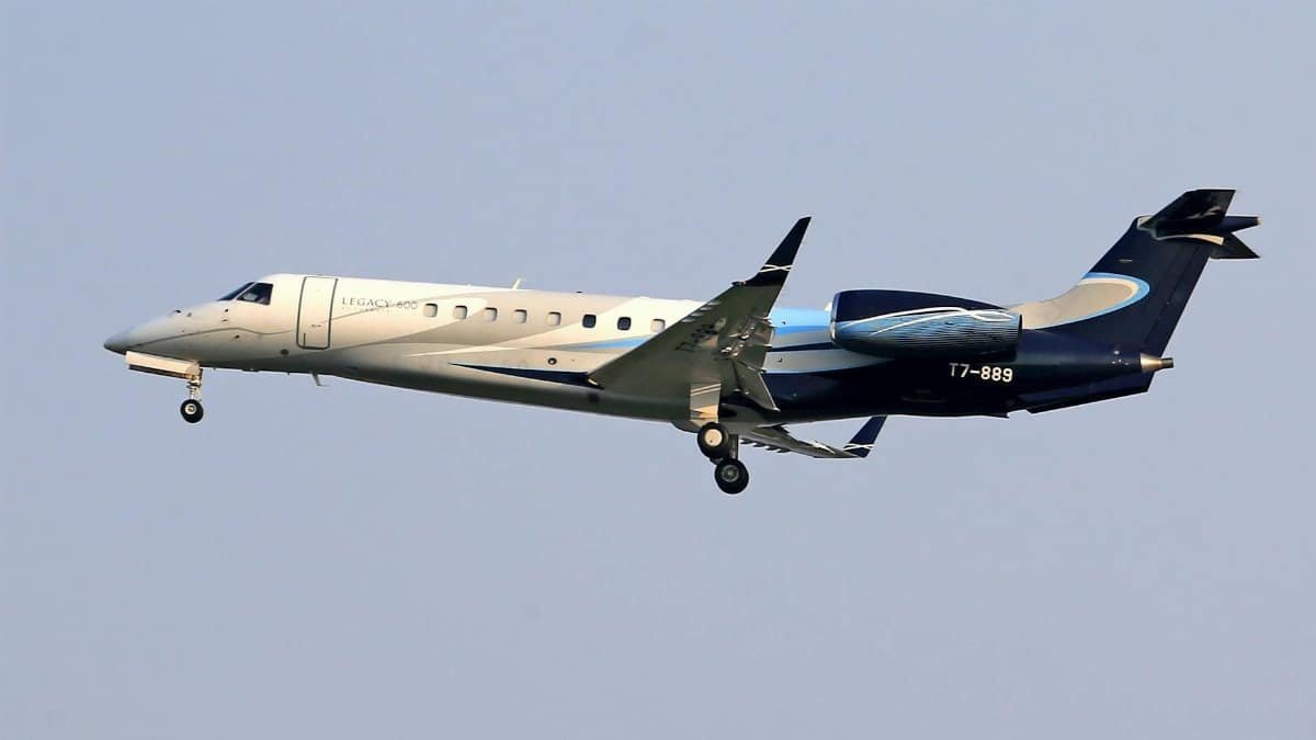 Embraer Legacy 600 private jet flying in clear blue sky, showcasing sleek design and elegance.