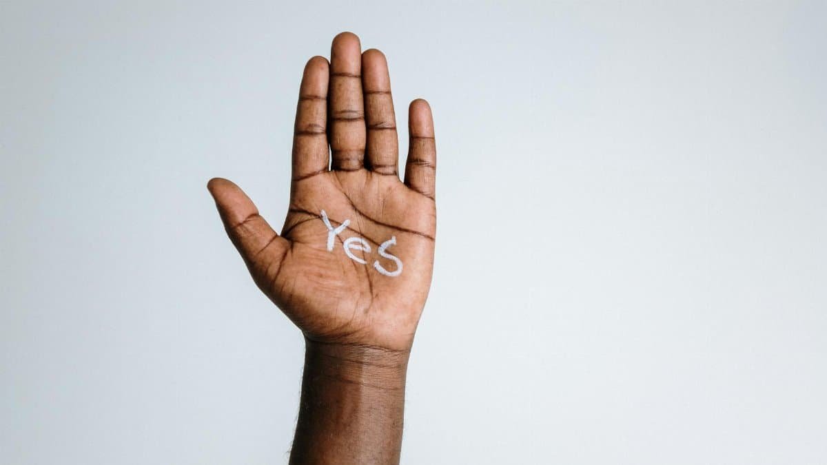 Close-up of a raised hand with 'Yes' written on the palm, symbolizing agreement and positivity.