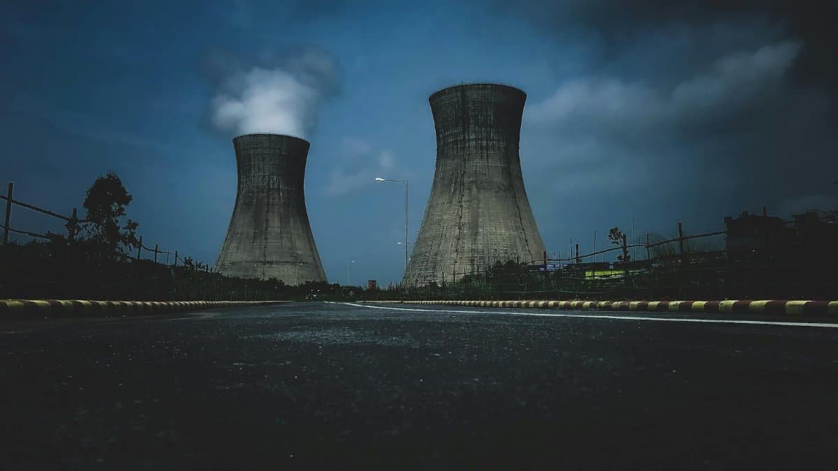 Moody view of industrial cooling towers with smoke against a twilight sky, emphasizing industry impact.