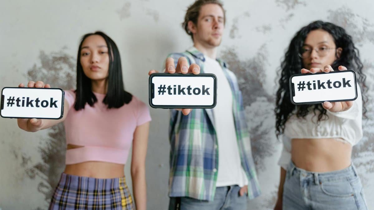 Group of young adults holding phones with #tiktok indoors, showcasing social media culture.