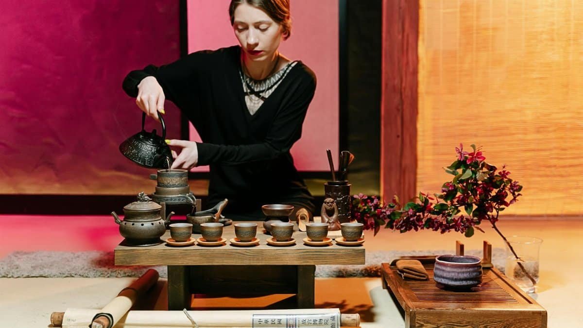 A serene traditional tea ceremony setup with a woman gracefully pouring tea.