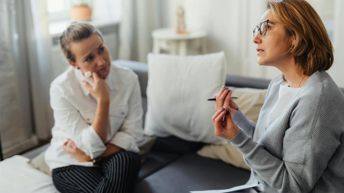 Two women engaged in a thoughtful counseling session in a cozy indoor setting.