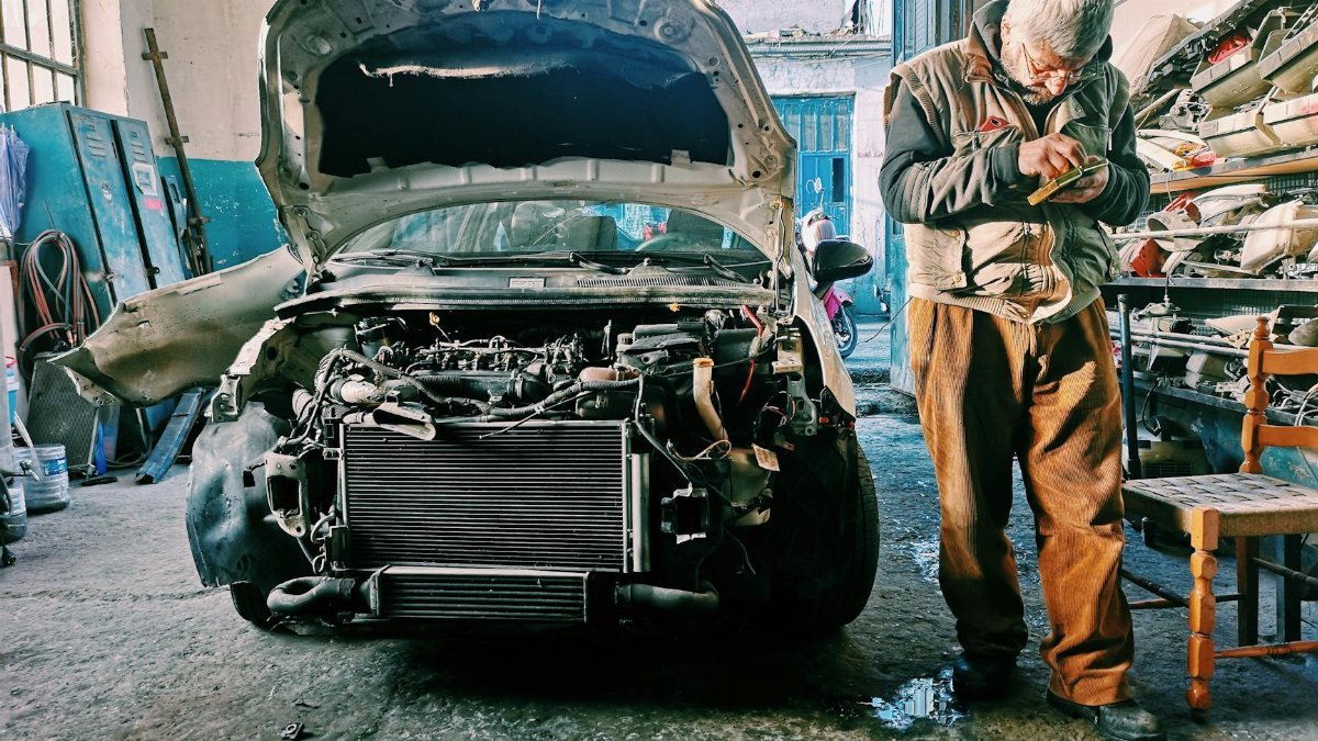 Mechanic repairing car in an auto workshop with the hood open showcasing the engine.