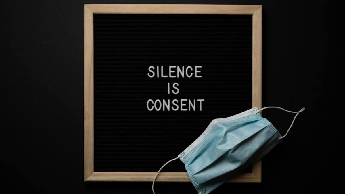 Composition of protective mask placed on wooden frame of blackboard on black background with lettering inspiring to speak up about problems