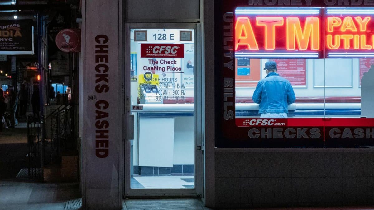 Neon-lit check cashing store with ATM services at night.