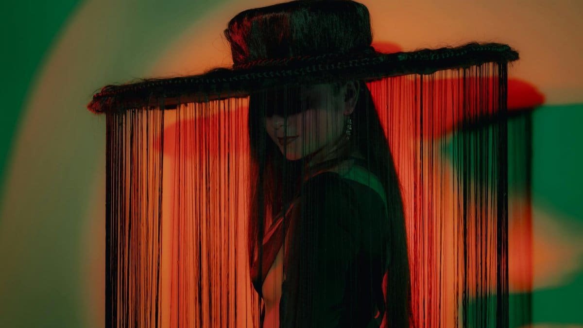 Artsy portrait of an adult with fringe hat, dramatic lighting.