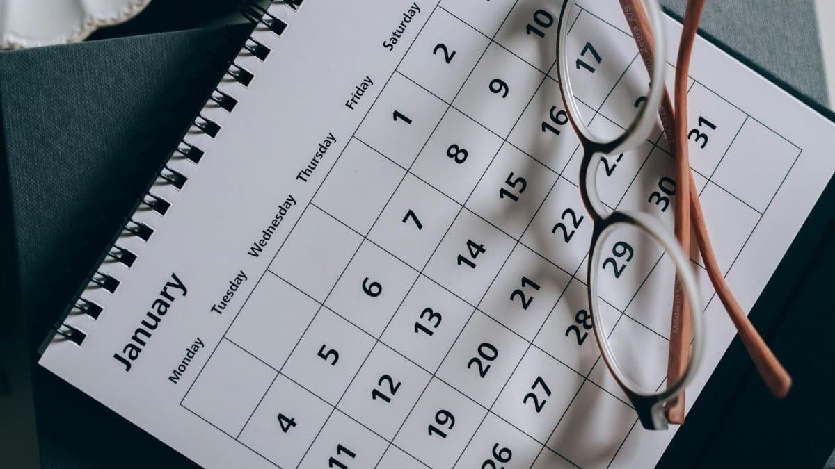 A close-up of a January calendar with eyeglasses on a table, emphasizing planning and organization.