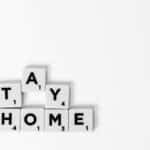A conceptual image with the message "Stay Home" spelled out using Scrabble tiles on a white background.