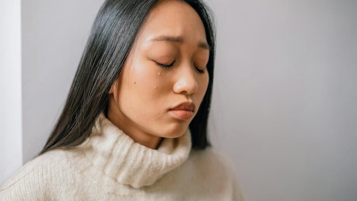 Close-up of an Asian woman with tears, showcasing emotional depth and sadness.