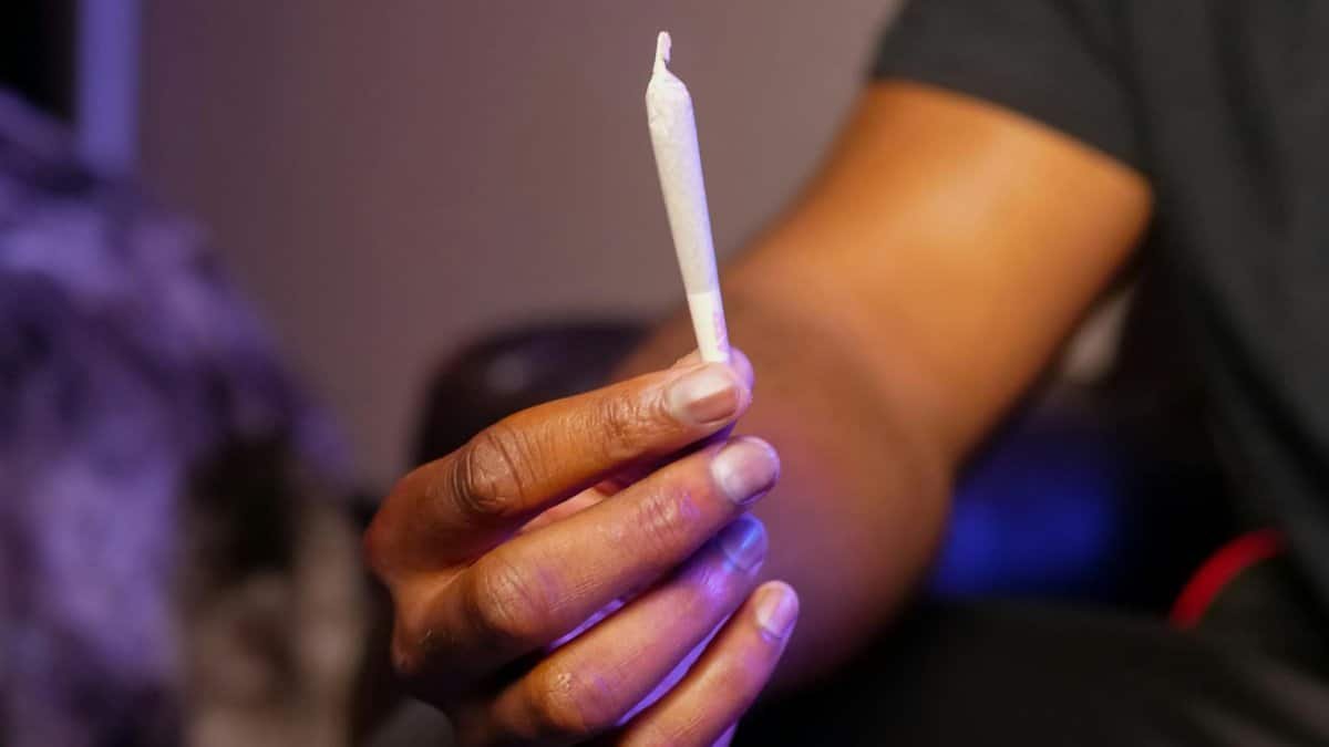 Close-up of a hand holding a cannabis joint, highlighting recreational marijuana use.