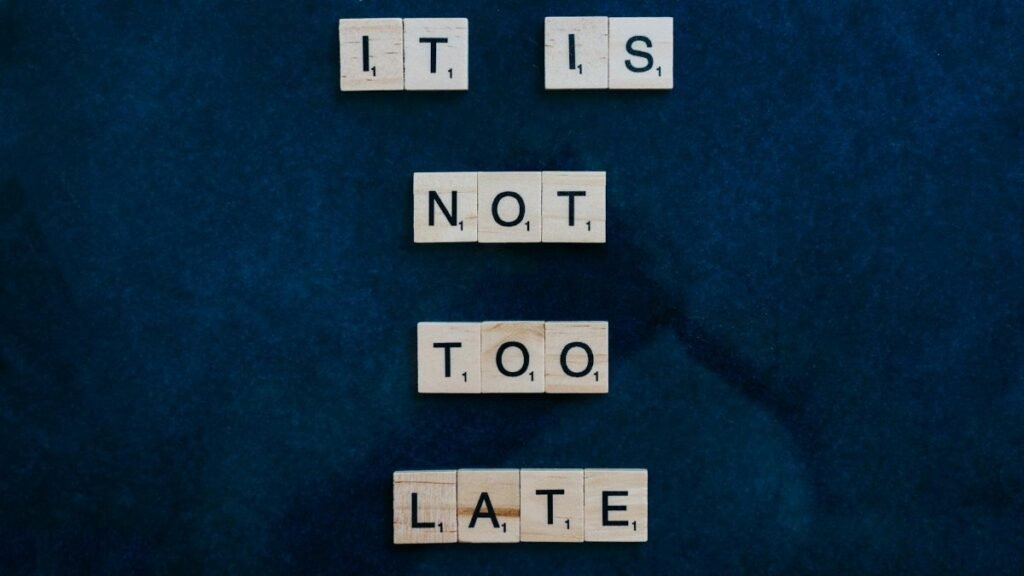 An inspiring message formed with wooden letter tiles on a dark surface: 'It is not too late'.