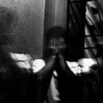 Grayscale image of a man covering his face, evoking themes of fear and introspection.