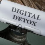 An overhead view of a typewriter printing 'Digital Detox' on wooden background.