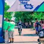 A cyclist reaches the finish line, cheered by a vibrant crowd at an outdoor race event.