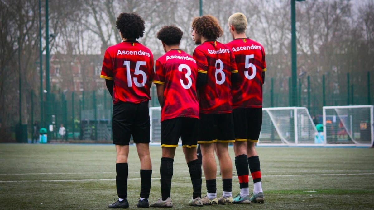 Four soccer players in red jerseys stand on the field, preparing for the game.
