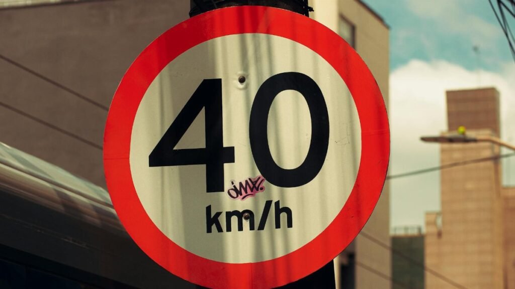 Close-up of a 40 km/h urban speed limit sign with graffiti in a city setting.
