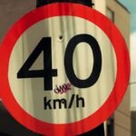 Close-up of a 40 km/h urban speed limit sign with graffiti in a city setting.