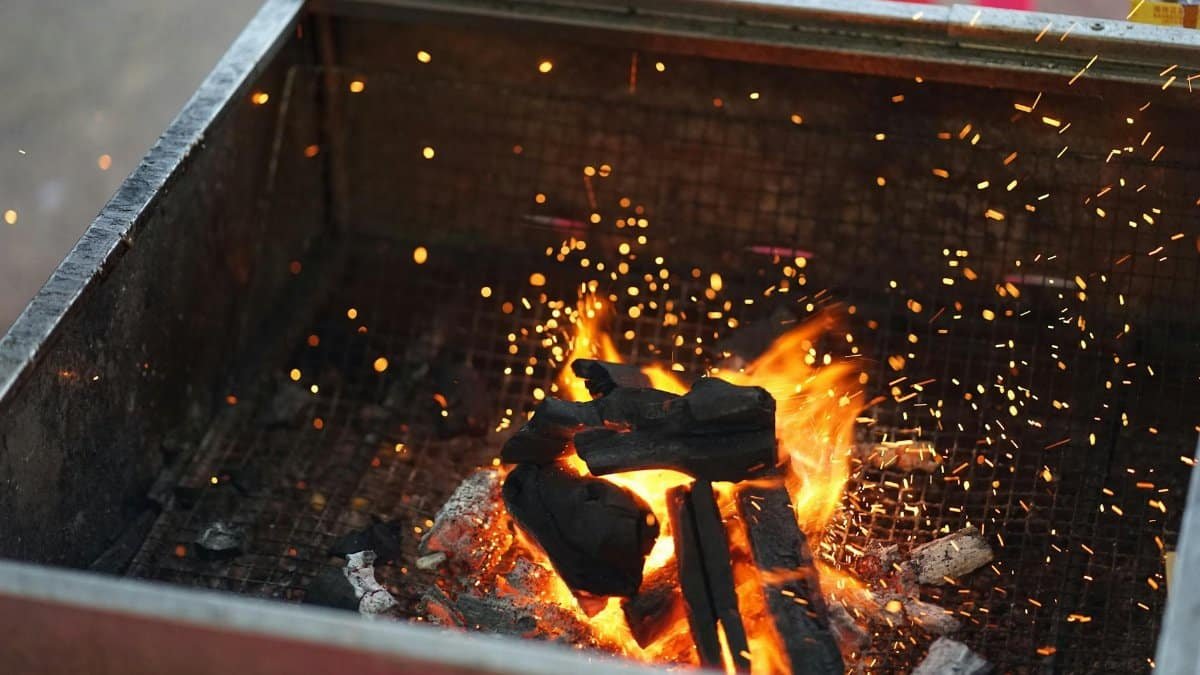 Lively outdoor charcoal grill fire with glowing embers and sparks.