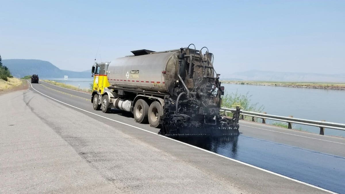 Paving truck applying asphalt on a highway near a lake in Klamath Falls, Oregon.