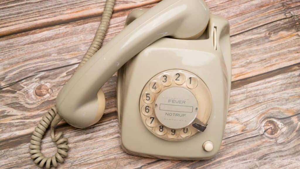 Retro rotary phone with dial on rustic wooden surface, nostalgic feel.