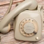 Retro rotary phone with dial on rustic wooden surface, nostalgic feel.